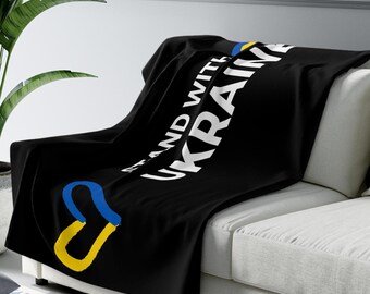 May include: Black fleece throw blanket with the text "Stand with Ukraine" in white and a yellow and blue heart symbol.