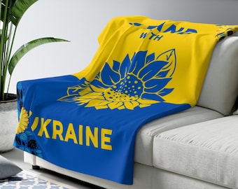 May include: A blue and yellow throw blanket with a sunflower design and the text "Stand with Ukraine".