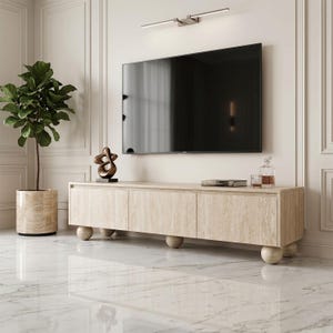 May include: A long, rectangular media console made of light beige travertine stone with a natural veined texture. The console features three cabinet doors and is supported by four large, spherical ball-shaped feet made of the same stone material.