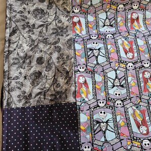 May include: A patchwork quilt with a black and white floral pattern, a black and white polka dot pattern, and a colorful pattern featuring Jack Skellington and Sally from The Nightmare Before Christmas.
