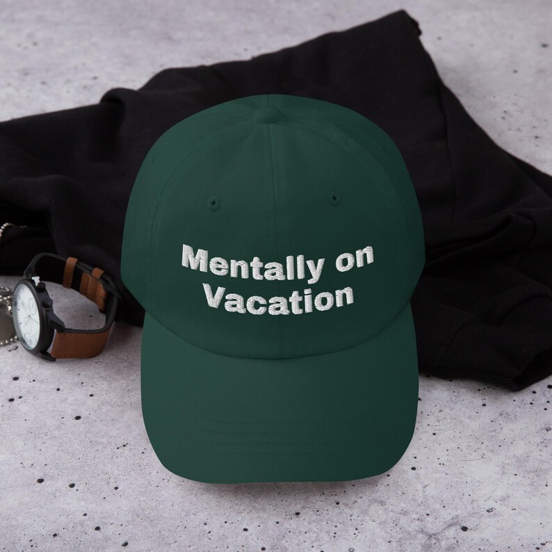 May include: A dark green baseball cap with white embroidered text that reads "Mentally on Vacation".