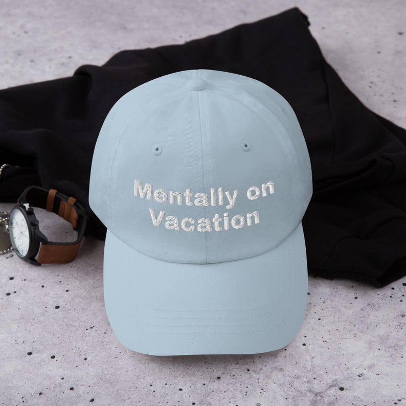 May include: A light blue baseball cap with white embroidered text that reads "Mentally on Vacation".