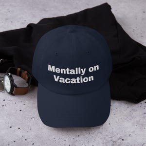 May include: A navy blue baseball cap with white embroidered text that reads "Mentally on Vacation".