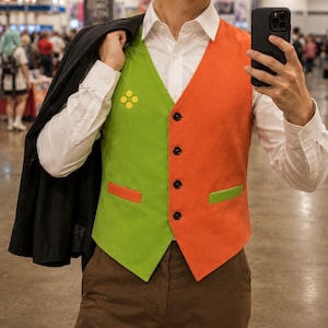 May include: A color-blocked vest featuring a lime green left side and an orange right side, with a four-dot yellow emblem on the chest, four black buttons, and contrasting pocket welts, worn over a white button-down shirt with brown trousers.