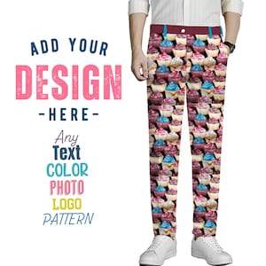 May include: A pair of white pants with a cupcake pattern. The pants have a red waistband and are made of a lightweight fabric. The cupcakes are pink, blue, and yellow.