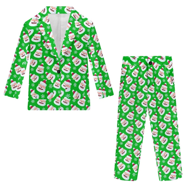 May include: A green Christmas suit set featuring a blazer and pants. The suit is covered in a pattern of Santa Claus faces and snowflakes. The blazer has a single button closure, and the pants have a button and zipper closure.