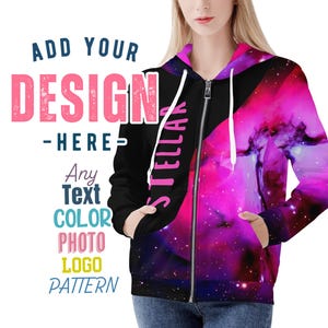 Peut inclure: Un sweat à capuche noir zippé avec un imprimé galaxie rose et violet. Le texte "STELLAR" est imprimé sur le côté gauche du sweat. Le texte "ADD YOUR DESIGN HERE" est imprimé sur le côté gauche de l'image.
