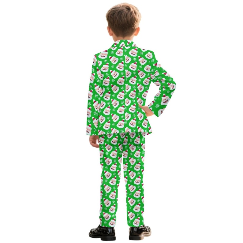 May include: A green Christmas suit with a repeating pattern of Santa Claus faces and snowflakes. The suit includes a blazer and matching pants. The child is wearing black dress shoes.
