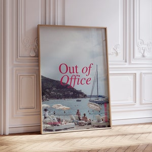May include: A framed poster with a photo of a beach scene and the text "Out of Office" in pink letters.