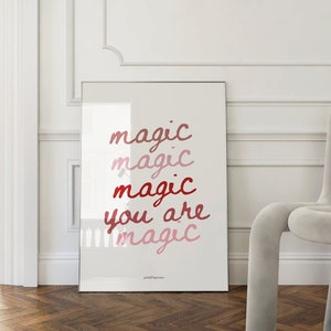 May include: A framed print with the text "magic magic magic you are magic" in shades of pink and red on a white background.