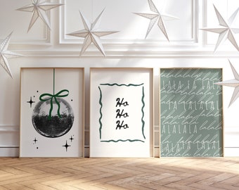 May include: Three framed prints with a Christmas theme. The print on the left features a black and white disco ball ornament with a green ribbon. The middle print has the words "Ho Ho Ho" written in black. The print on the right has a green background with the words "lala lala lala" written in white.