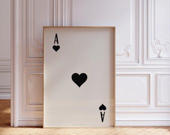 May include: A framed print of the Ace of Hearts playing card. The card is black and white with a large black heart in the center. The card is framed in a light wood frame.