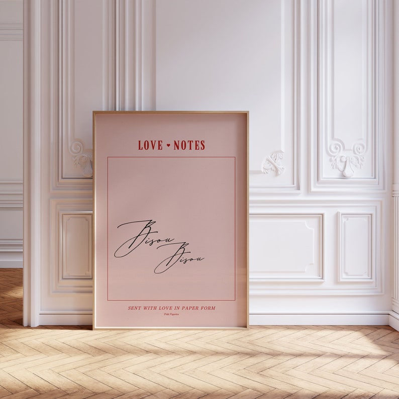 May include: A pink poster with a gold frame, featuring the text "LOVE NOTES" in red, a handwritten "Bisou Bisou" in black, and the text "SENT WITH LOVE IN PAPER FORM" in red.