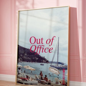 May include: A framed print with a photo of a beach scene with people relaxing on lounge chairs. The text "Out of Office" is printed in red on the print.