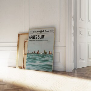May include: A framed print of a newspaper titled "The New York News" with the headline "APR&Egrave;S SURF." The image shows people surfing in the ocean. The text "Exclusive report: Saltwater heals Everything" is also visible.