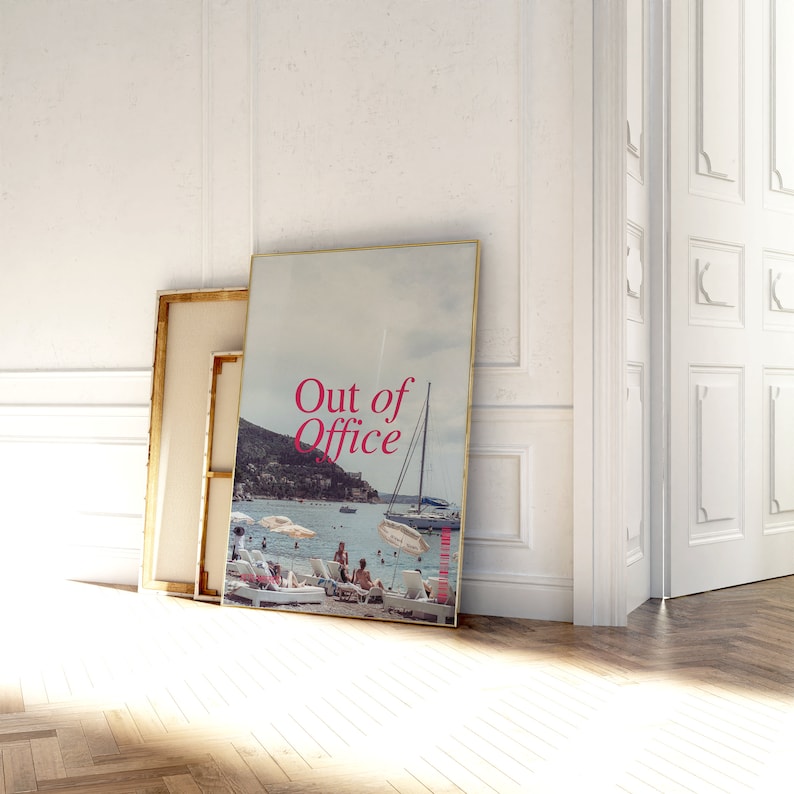 May include: A framed poster with a photo of a beach scene with people relaxing on lounge chairs and a sailboat in the water. The poster has the text "Out of Office" in pink letters.
