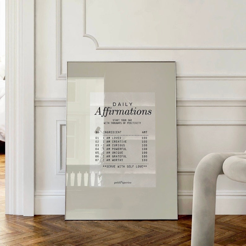 K&ouml;nnte beinhalten: Ein gerahmter Druck mit wei&szlig;em Hintergrund und schwarzem Text, der "T&auml;gliche Affirmationen" lautet und eine Liste von Affirmationen mit entsprechenden Nummern und Betr&auml;gen enth&auml;lt. Der Text unten lautet "Mit Selbstliebe servieren" und "petit Paperies".