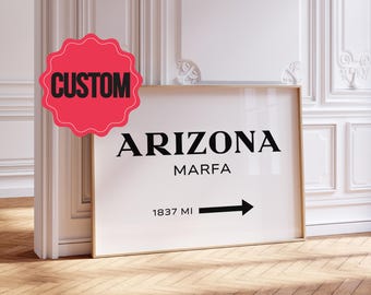 May include: A rectangular framed print featuring the black text ARIZONA, MARFA, and 1837 MI with a right-pointing arrow. A pink scalloped circular badge with the black text CUSTOM is positioned in the upper left corner of the print.
