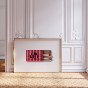 May include: A red and white striped matchbox with the text "CIAO BELLA" printed on the front. The matchbox is open and contains a row of wooden matches.