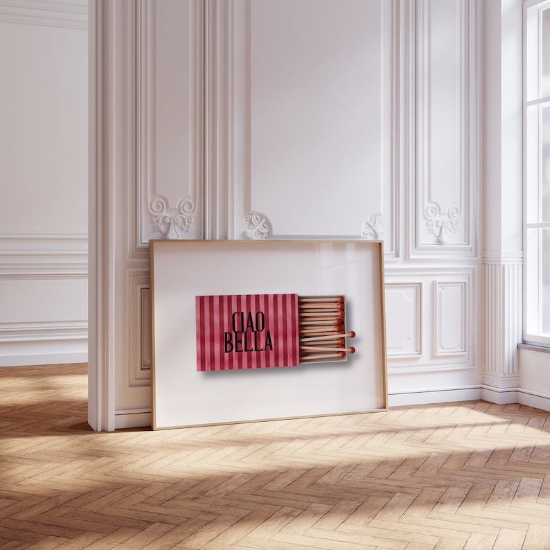 May include: A framed print of a red and white striped matchbox with the text "Ciao Bella" printed on the front. The matchbox is open and contains a row of matches.