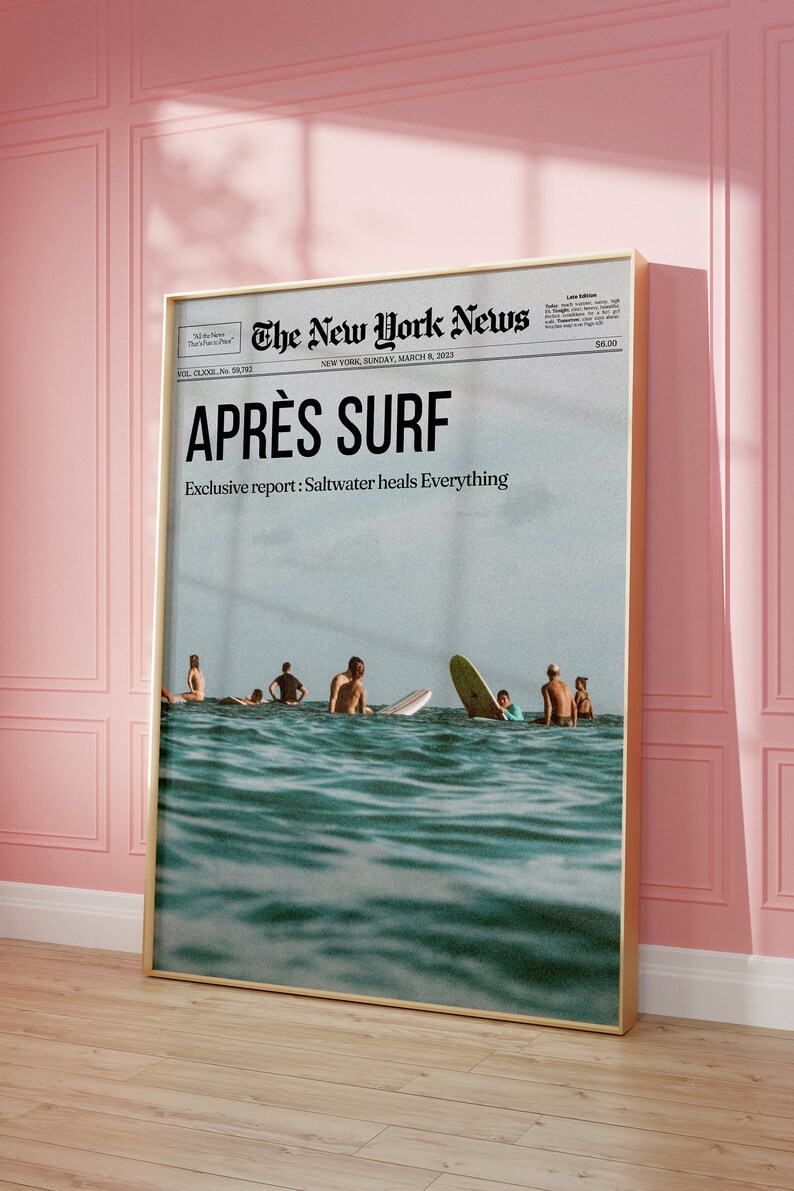 May include: Framed print of a newspaper front page titled "The New York News" with the headline "APR&Egrave;S SURF." The image shows surfers in the ocean. The text "Exclusive report: Saltwater heals Everything" is also visible.