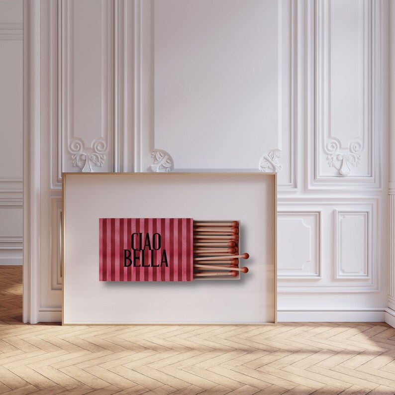 May include: A framed print of a red and white striped matchbox with the text "CIAO BELLA" on the front. The matchbox is open and the matches are visible.