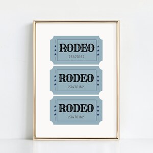 Puede incluir: Tres talones de entradas azules con la palabra "RODEO" en texto negro y el n&uacute;mero "23470162" impreso en cada uno. Los boletos est&aacute;n enmarcados en un marco dorado.