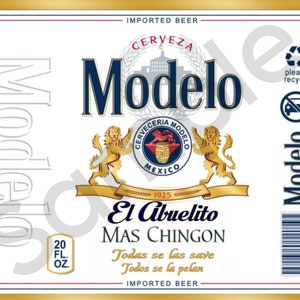 May include: A white beer can label with a gold border. The label features the text "Modelo" in blue, "Cerveza Modelo" in a circle with a lion and a barrel, and the text "El Abuelito Mas Chingon" in a banner. The label also includes the text "Todas se las save Todos se la pelan" and "Imported Beer".
