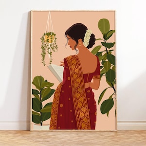 May include: A woman in a red and gold sari is reading a book. She is standing in front of a pink background with green plants.