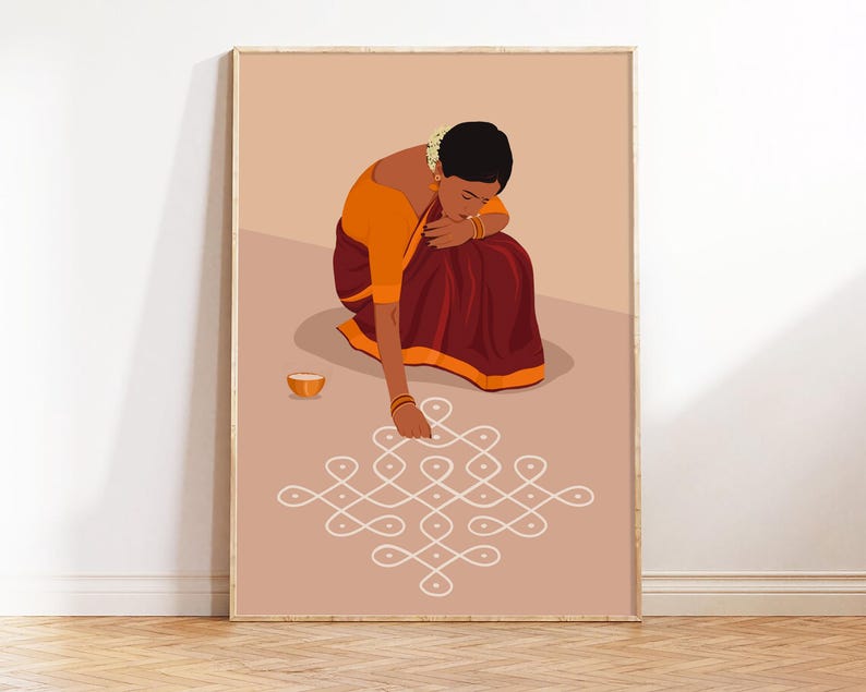 May include: A framed art print shows a woman in traditional Indian clothing, kneeling to draw a white geometric pattern on a light brown surface. She wears an orange blouse and a maroon skirt. A small orange bowl is nearby.