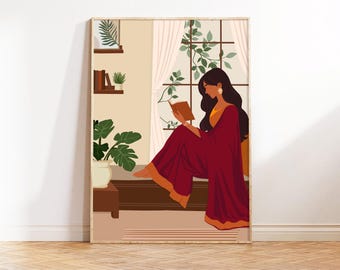 May include: A woman in a red and gold sari sits by a window reading a book. The window has a view of green plants and a white curtain. The woman is sitting on a brown couch with a brown rug on the floor.