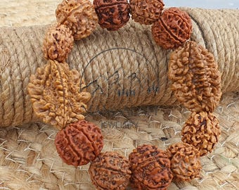 May include: A bracelet made of brown, textured beads. The beads vary in size and shape, with a natural, organic appearance. The bracelet is displayed on a woven surface, showcasing its earthy tones and intricate details. The beads are strung together, forming a complete circle.