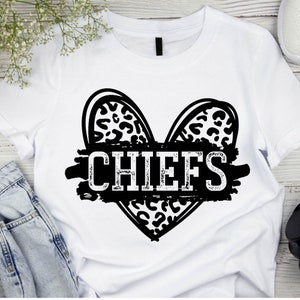 Könnte beinhalten: Weißes T-Shirt mit einem schwarzen herzförmigen Design mit Leopardenmuster. Das Wort "CHIEFS" ist in weißen, fetten Buchstaben über dem Herzen aufgedruckt.