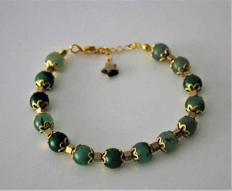 May include: A green gemstone bracelet with gold accents and a star charm. The bracelet is made of round beads with a gold filigree design.