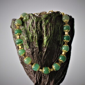 May include: A green gemstone bracelet with gold accents. The bracelet is made of round green stones with gold metal spacers between each stone.