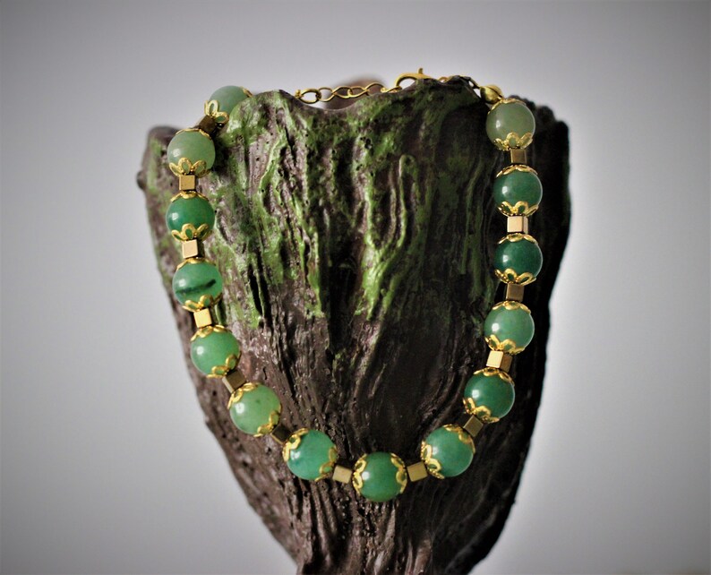 May include: A green gemstone bracelet with gold accents. The bracelet is made of round green stones with gold metal spacers between each stone.
