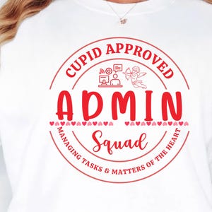 May include: White sweatshirt with a red graphic that says "Cupid Approved Admin Squad" in a circular design. The design includes a cupid with a bow and arrow, hearts, and office-related icons.