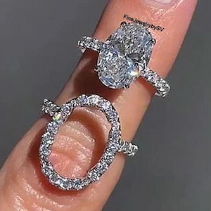 Może przedstawiać: Dwa diamentowe pierścionki. Jeden pierścionek ma diament o owalnym szlifie z oprawą halo. Drugi pierścionek to wysadzana diamentami obrączka w owalnym kształcie. Pierścionki są prezentowane na palcu. Widoczny jest tekst "FineJewelrybySV".