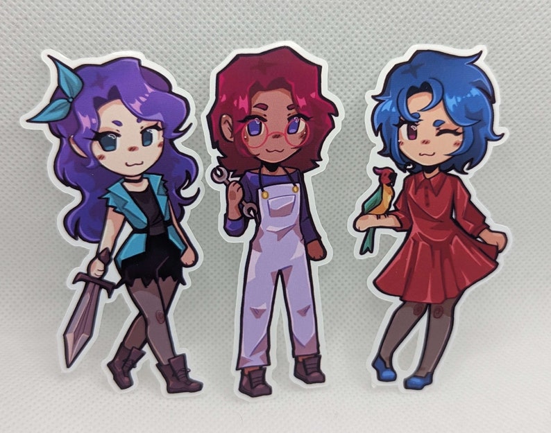 May include: Three cartoon character stickers with different colored hair and outfits. The character on the left has purple hair and is wearing a blue jacket and black pants. The character in the middle has red hair and is wearing a blue jumpsuit. The character on the right has blue hair and is wearing a red dress.