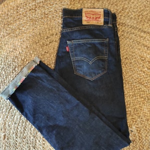 Könnte beinhalten: Eine dunkelblaue Jeanshose mit einem Levi's-Etikett auf der Gesäßtasche. Das Etikett lautet "Levi Strauss & Co.  Original  501®  W31 L32".