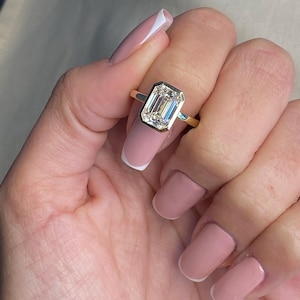 May include: A gold ring with a large, clear emerald-cut diamond.