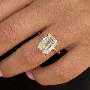 May include: A gold ring with a large, clear emerald-cut diamond.
