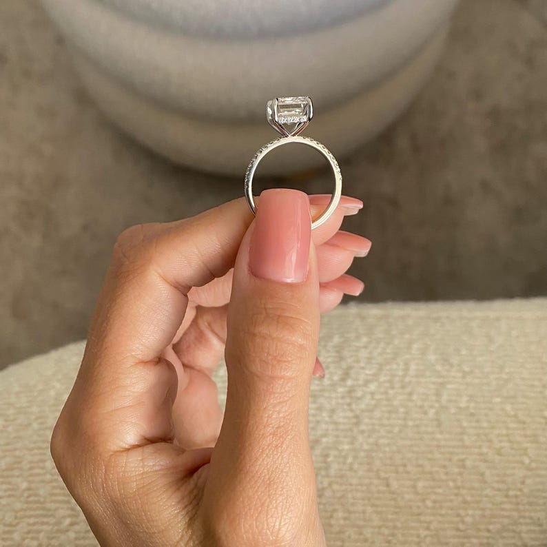 Op de afbeelding: Een zilveren ring met een grote, vierkante diamant die in een pav&eacute;-setting is gezet. De band is ook pav&eacute;-gezet met kleinere diamanten.