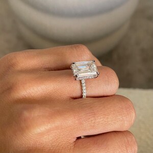 Op de afbeelding: Een zilveren ring met een grote, rechthoekige smaragd geslepen diamant gezet in een pav&eacute; setting. De band is ook gezet met kleinere diamanten.