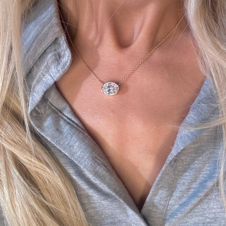 May include: A gold chain necklace with a small oval pendant featuring a cluster of clear stones.
