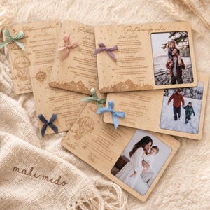 May include: A collection of rectangular wooden plaques featuring engraved text, illustrations of hot air balloons and mountains, and attached fabric ribbons in various colours. Each plaque includes a rectangular cutout for a photograph.
