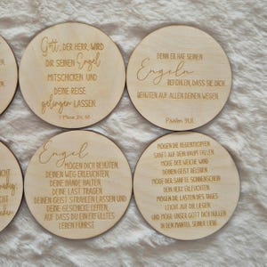 Puede incluir: Un conjunto de posavasos redondos de madera clara con textos grabados en alem&aacute;n. Los posavasos presentan citas inspiradoras escritas en una fuente elegante. El conjunto se muestra sobre un fondo claro.