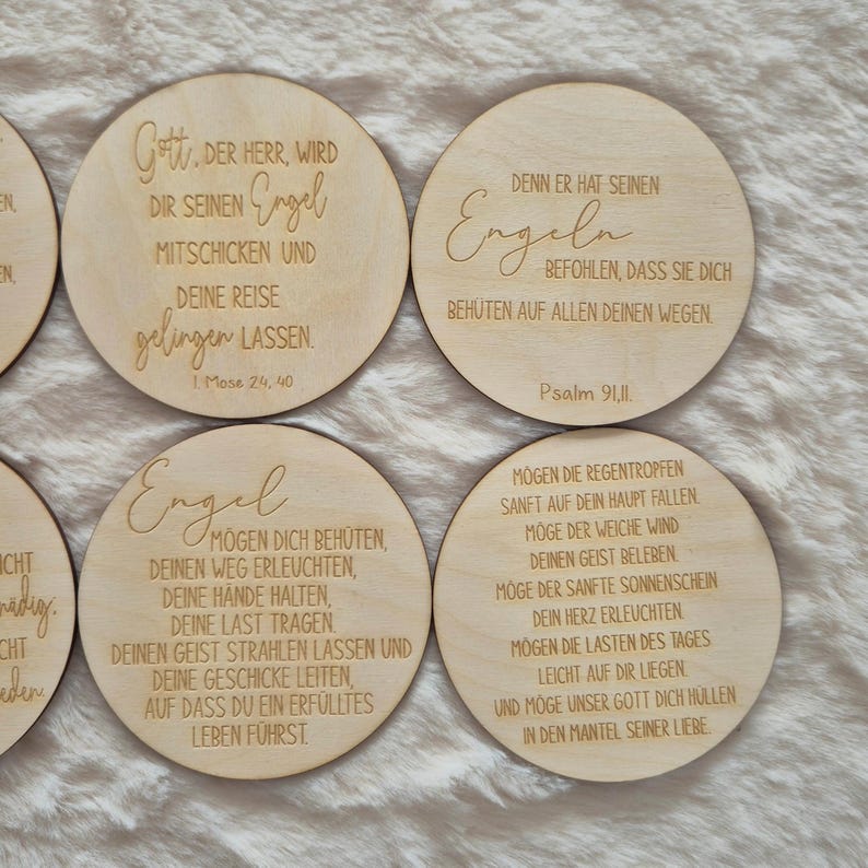 Puede incluir: Un conjunto de posavasos redondos de madera clara con textos grabados en alem&aacute;n. Los posavasos presentan citas inspiradoras escritas en una fuente elegante. El conjunto se muestra sobre un fondo claro.