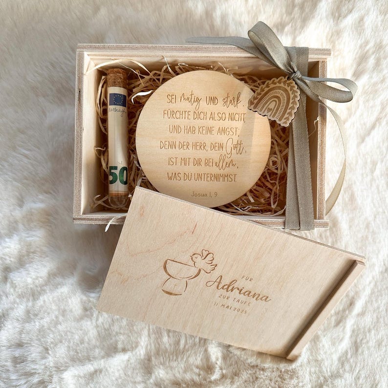 Puede incluir: Caja de regalo de madera marr&oacute;n claro, que contiene una placa redonda de madera con texto grabado y una cinta decorativa. La caja tambi&eacute;n contiene un tubo de vidrio con un billete de 50. La tapa de la caja est&aacute; abierta, revelando una inscripci&oacute;n personalizada.