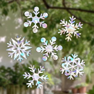 Könnte beinhalten: Sechs schimmernde Schneeflocken-Fensteraufkleber, jeder mit einem einzigartigen Design, perfekt, um jedem Fenster in der Weihnachtszeit einen festlichen Touch zu verleihen.